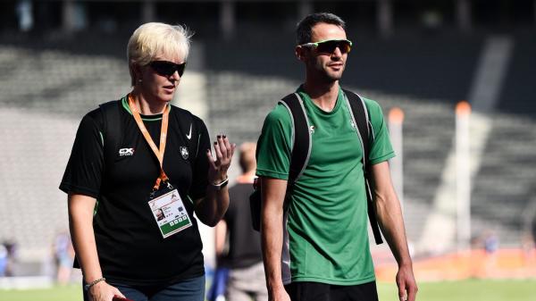 Female coach and male athlete walk and talk together. 