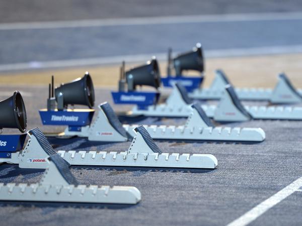 image of athletics starting blocks lined up on a blue athletics track