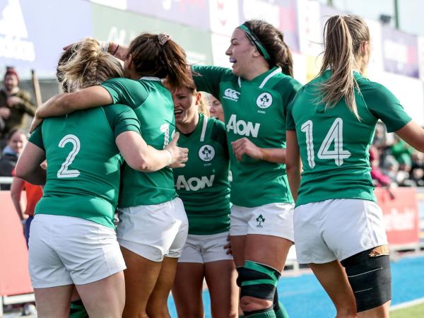 Irish women's rugby players celebrating together on the field