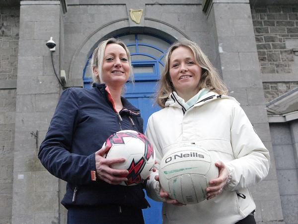 Two females stand in front of Limerick prison holding footballs