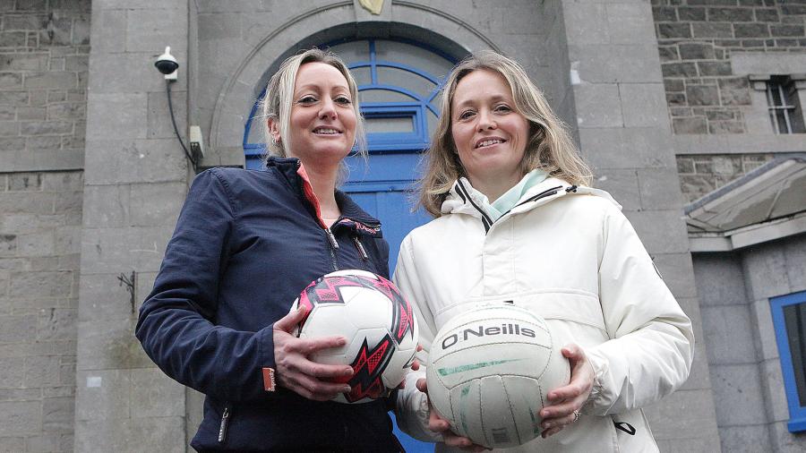 Two females stand in front of Limerick prison holding footballs
