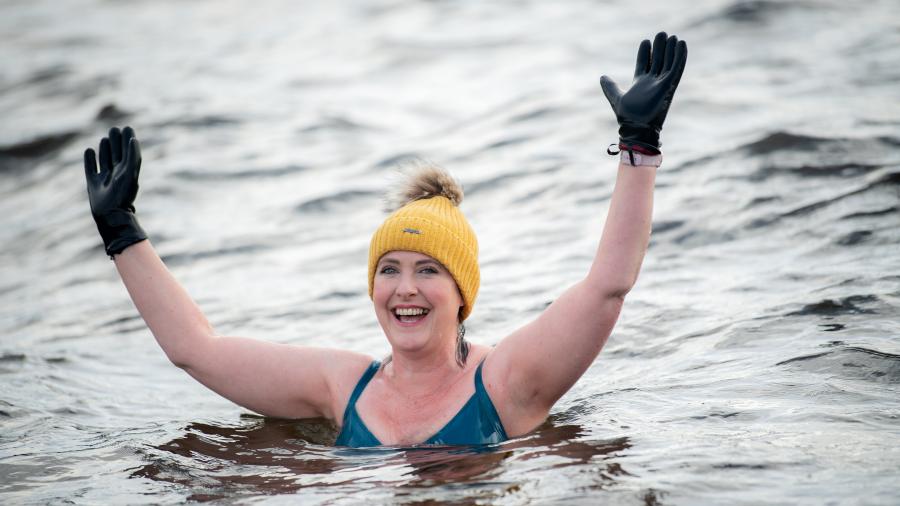 Karen stands in the water smiling with her arms in the air
