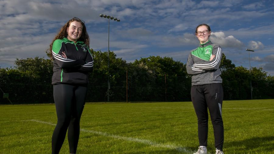 Kate Russell and Ciara Floyd stand on a soccer pitch with arms folded looking at the camera