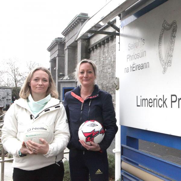 Two females stand in front of Limerick prison holding footballs