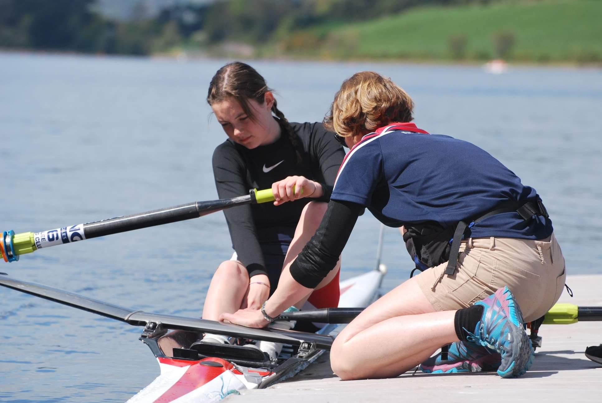 A coach helps a female rower in her boat