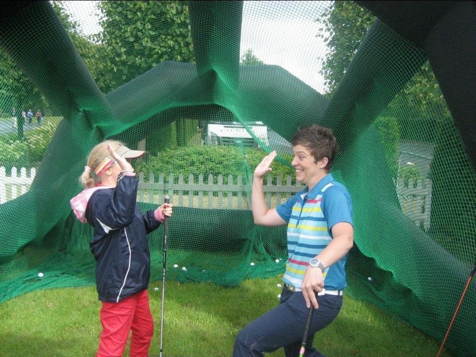 Female coach high fives a female athlete in a golf putting range