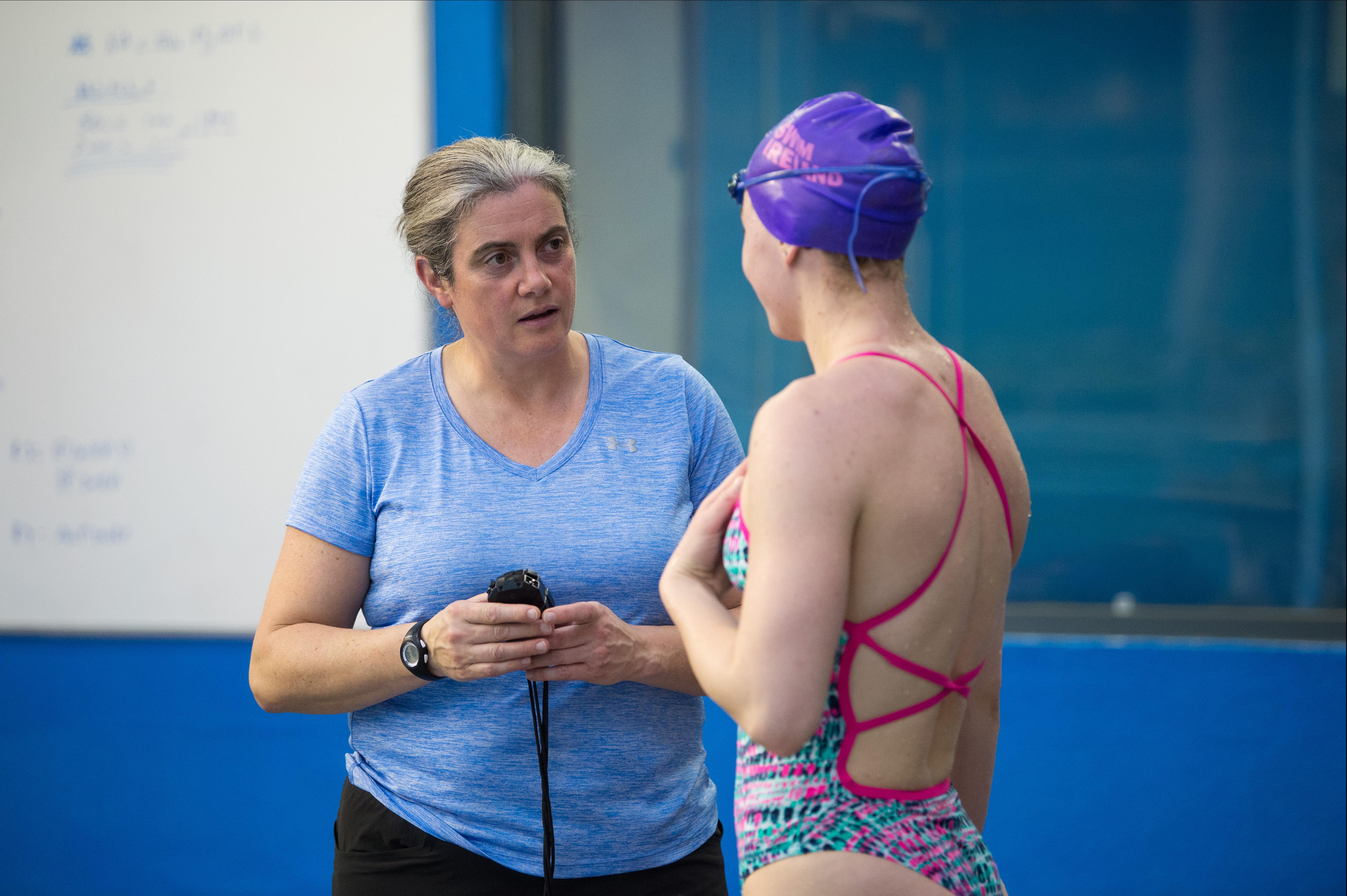 A swim coach chats to a female swimmer