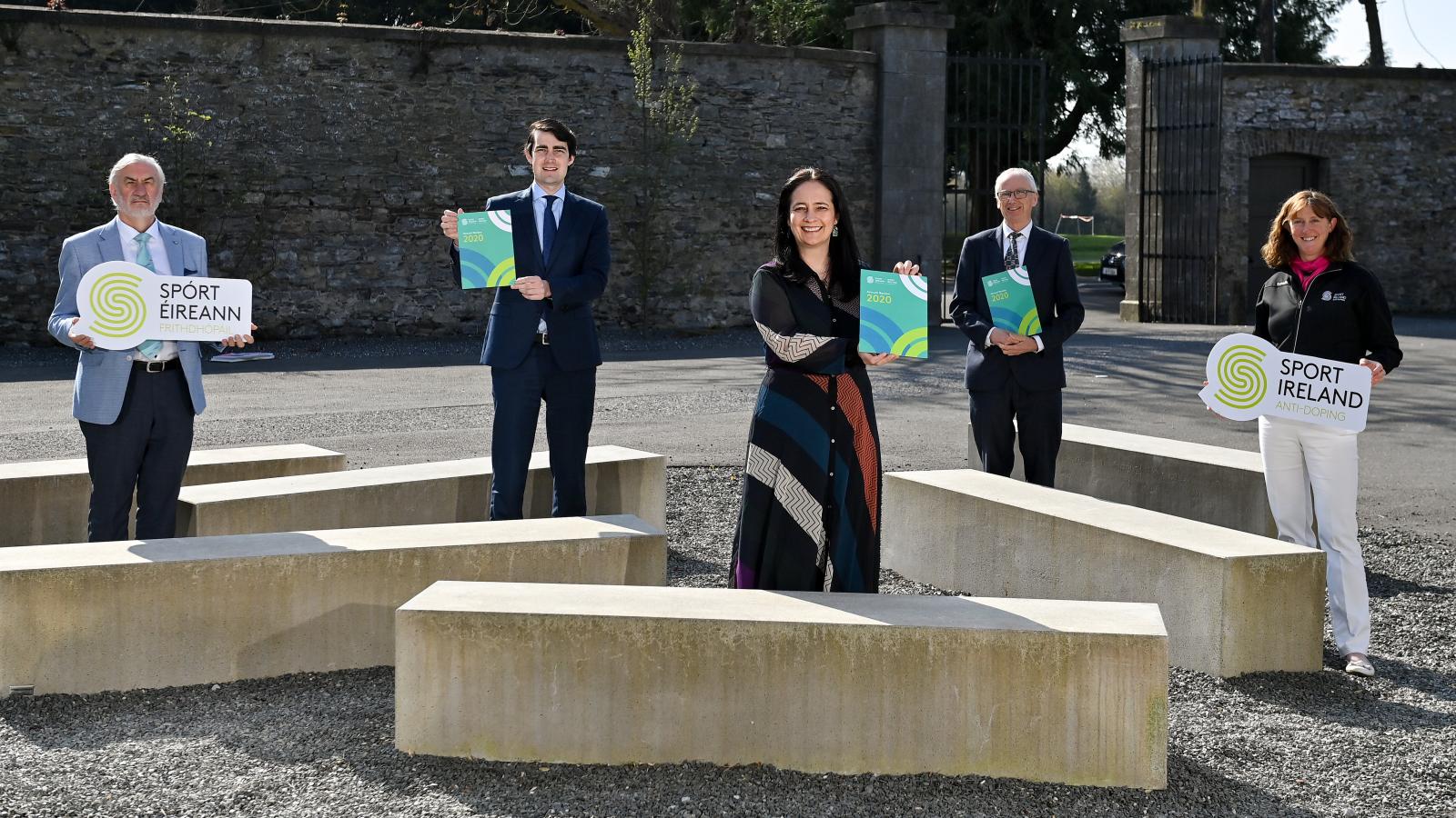 5 people standing holding a copy of the Anti Doping Review. From left to right - Kieran Mulvey, Minister Jack Chambers, Minister Catherine Martin, John Treacy, Dr. Una May