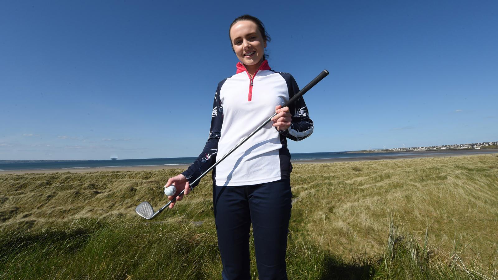 Sophie stands on a golf course holding a putter and ball