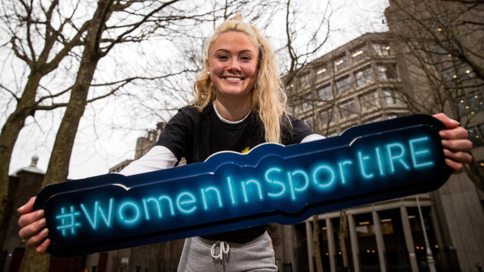 Woman holding a #WomenInSportIRE sign